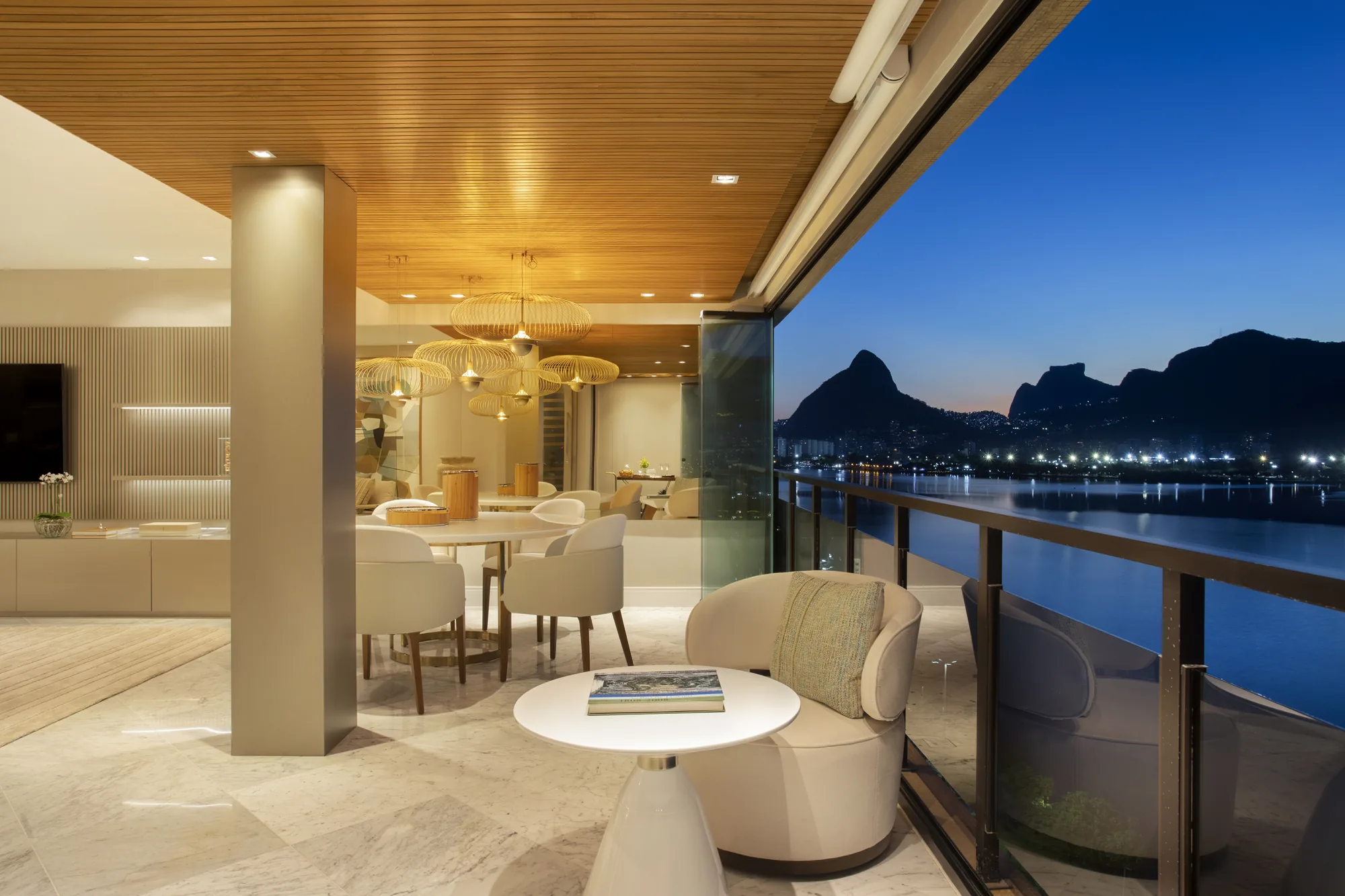 Varanda com forro de madeira ripada e vista para a Lagoa ao anoitecer